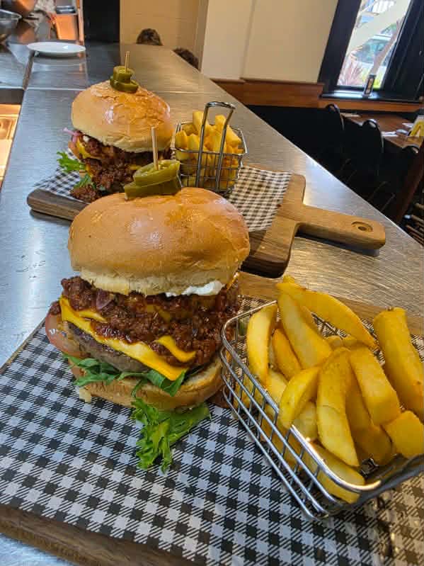 Loaded pub burgers served on a wooden board with chips at The Yardz Hotel