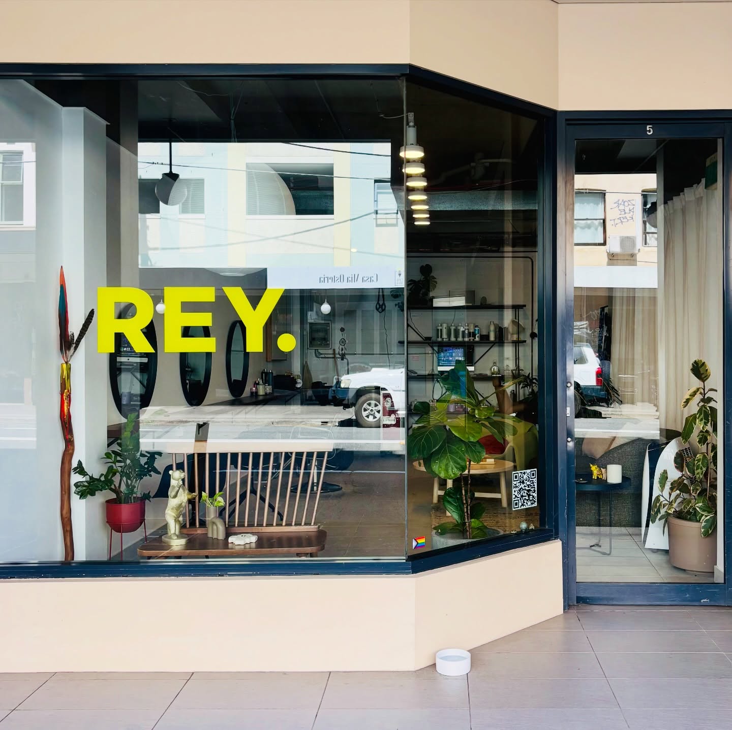 Rey Hair shopfront with large glass window, yellow REY. lettering and indoor plants