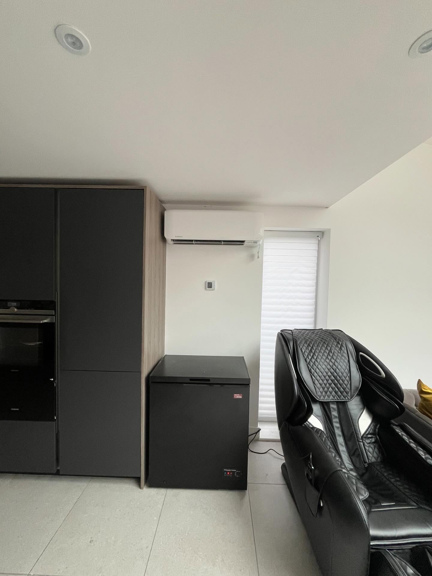 White wall-mounted split system air conditioner installed in a modern kitchen and living area