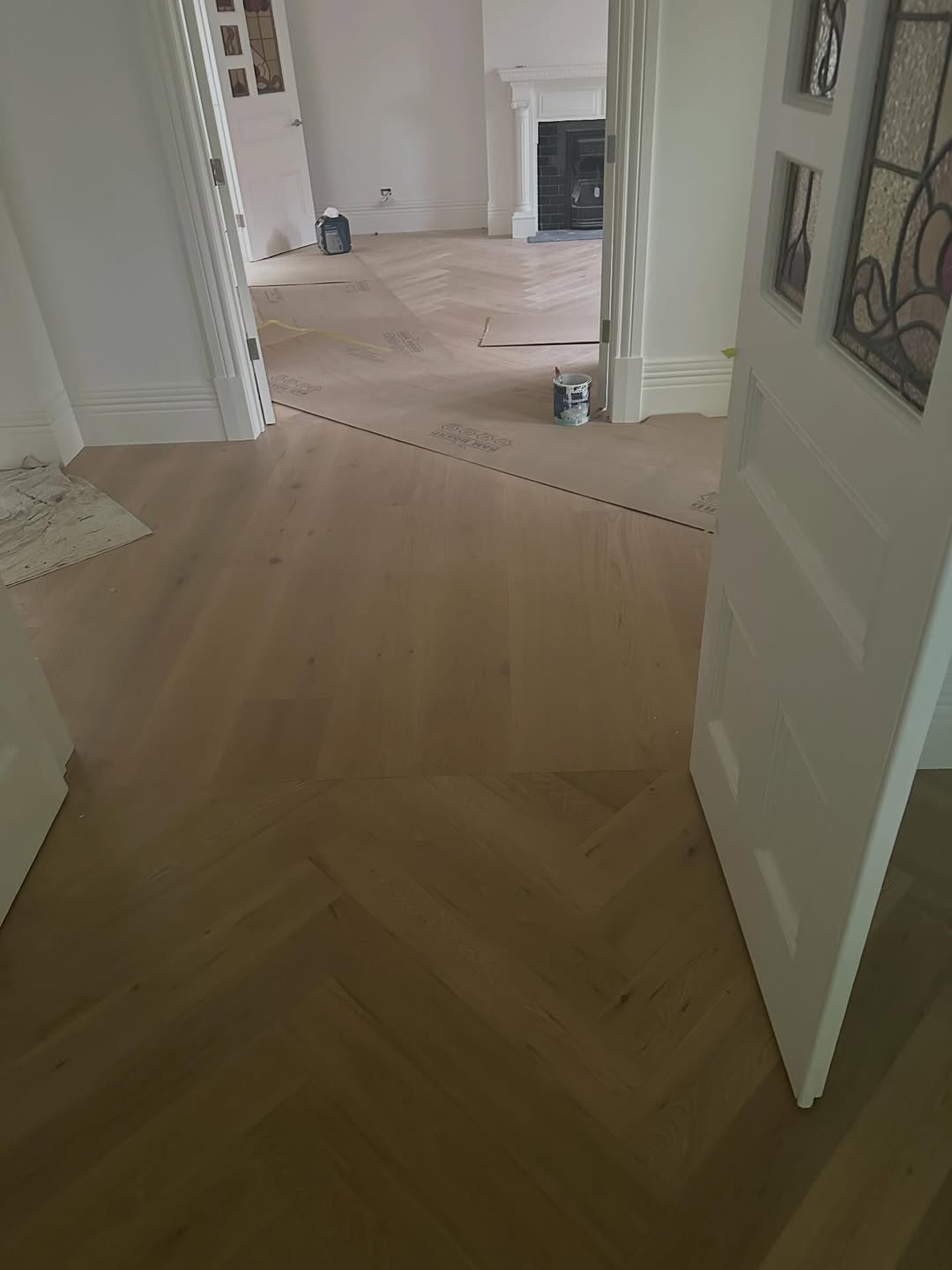 Herringbone timber flooring being installed in a classic Victorian-era home entry with stained glass door