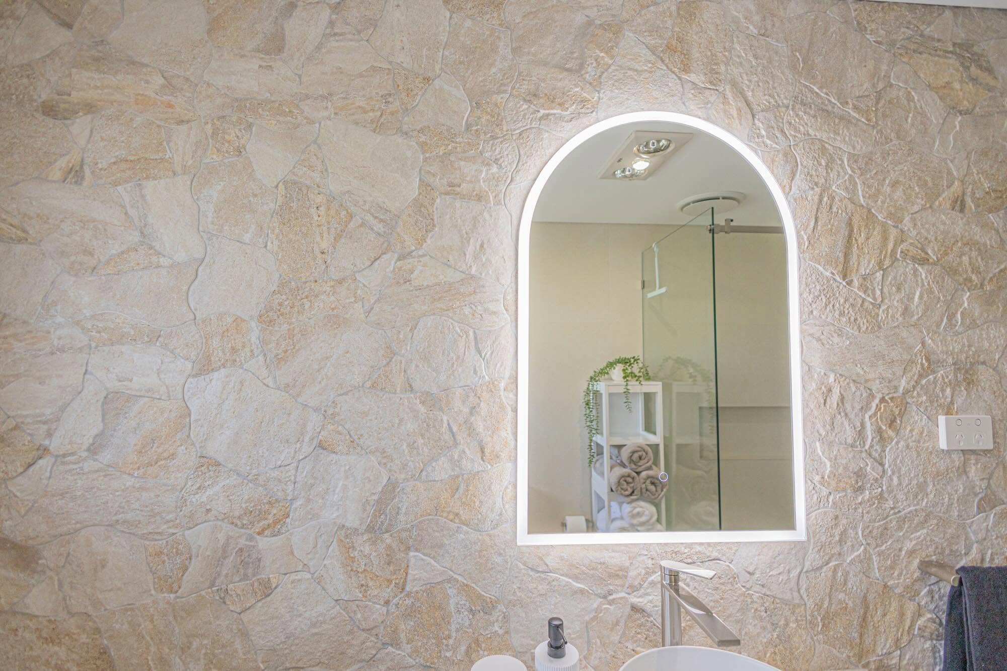 Natural stone-look feature wall tiles with an arched LED mirror – Wollondilly Tiles