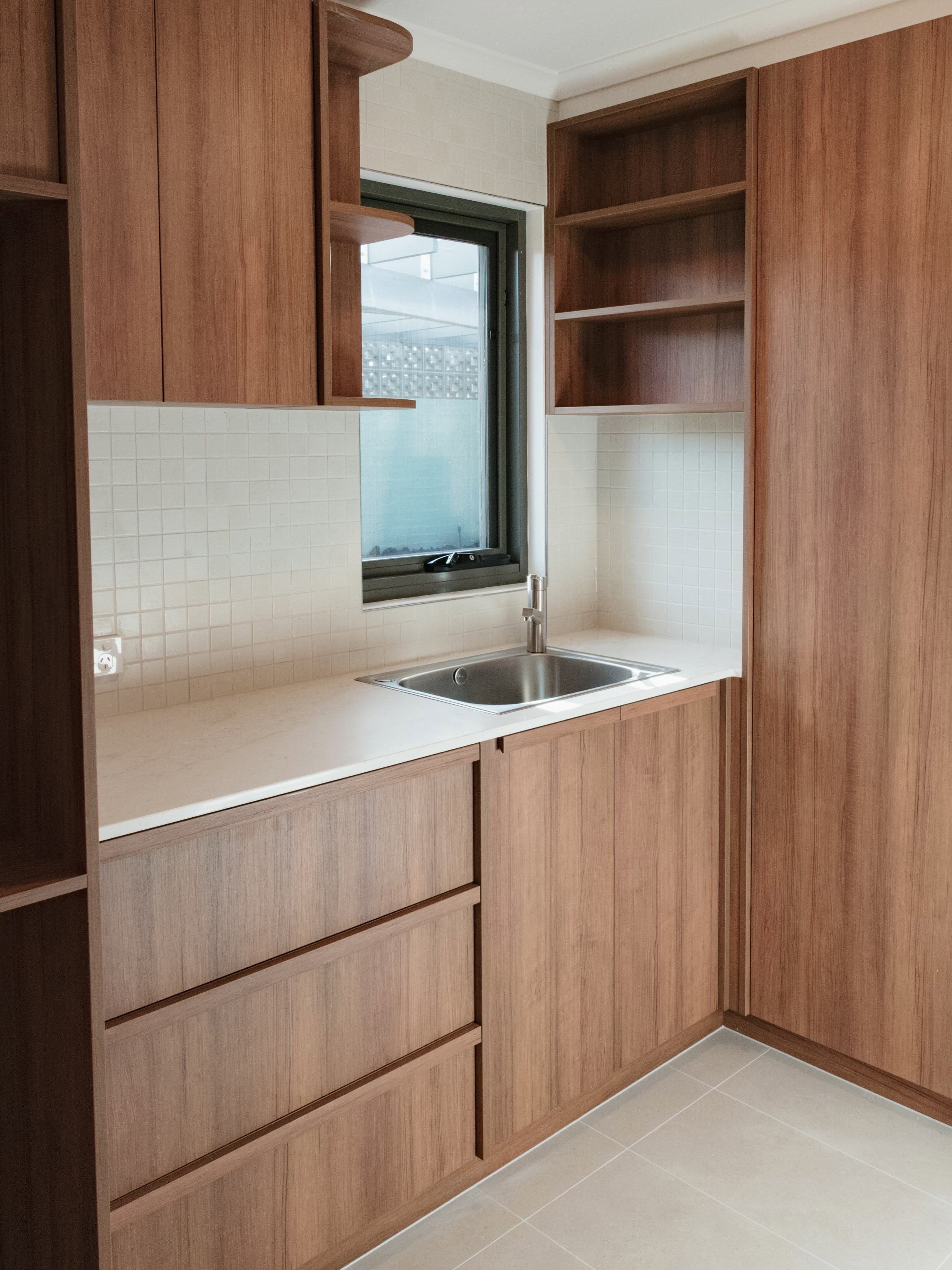 Built-in laundry cabinetry with sink, open shelving and overhead cupboards