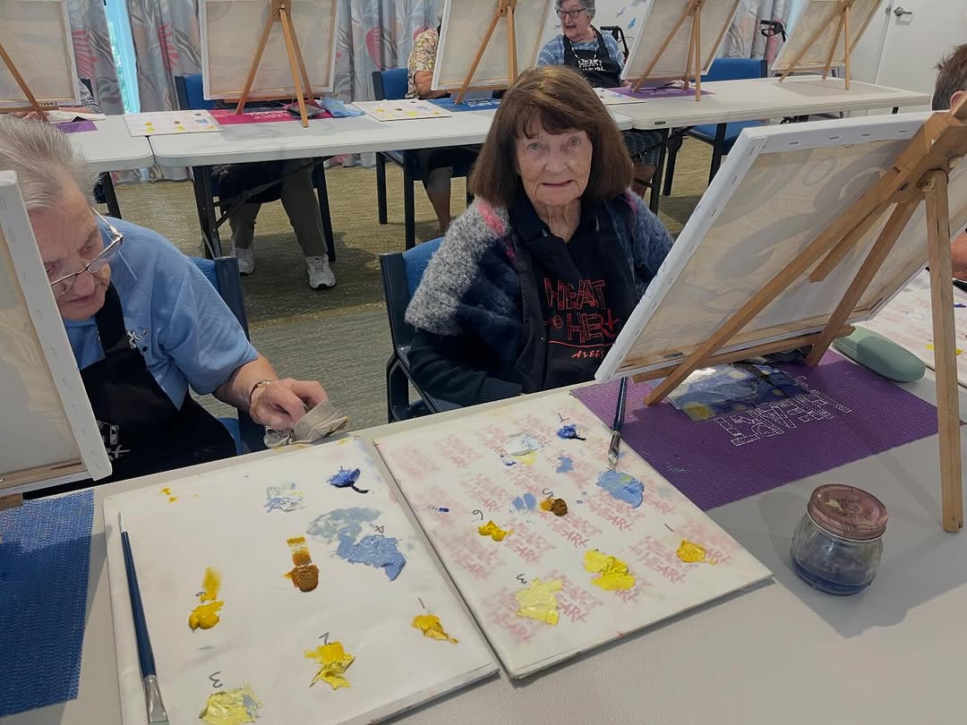 Senior resident working on her canvas with blue paint at a Heart to Heart session