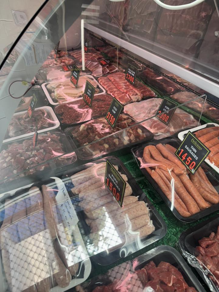 Overview of the full meat display including pork sausages and various cuts