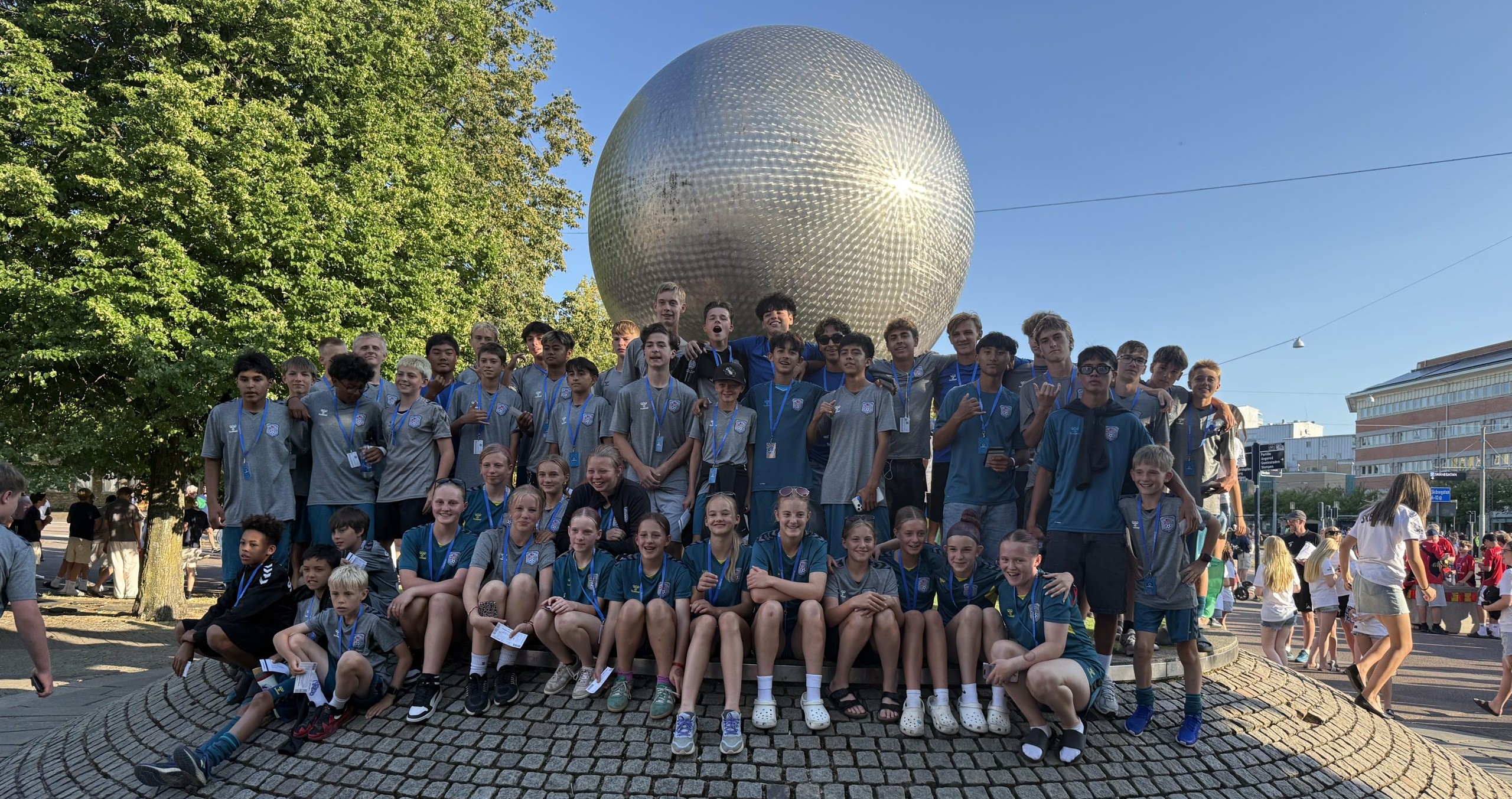 Scandia United youth soccer players celebrating together in front of the Gothia Cup landmark sphere in Gothenburg, Sweden