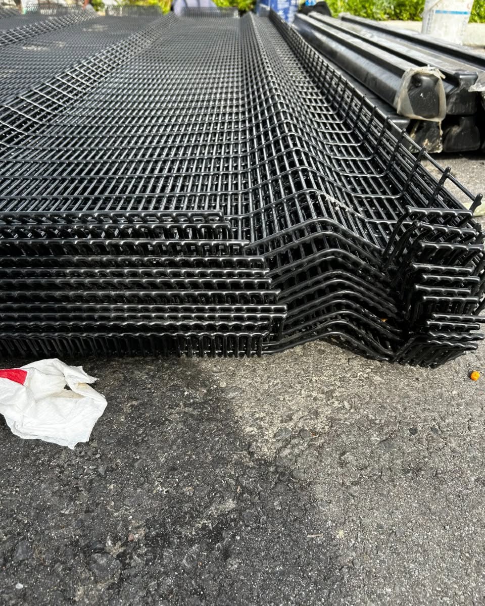 Black steel fence along a planted garden border at a commercial site
