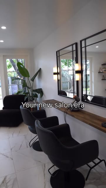 Elegant SJ Hairdressing salon interior with marble floors, black styling chairs and large framed mirrors