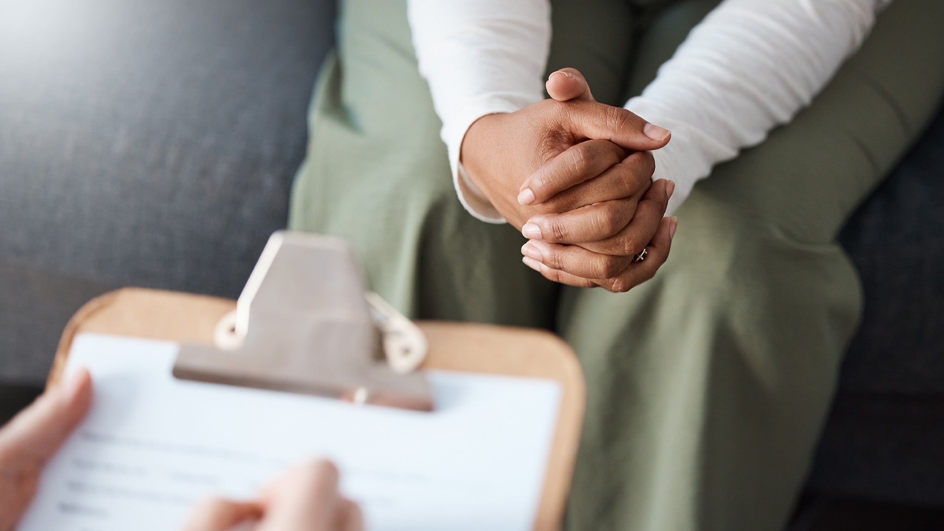 Seated client with clasped hands during a counseling session