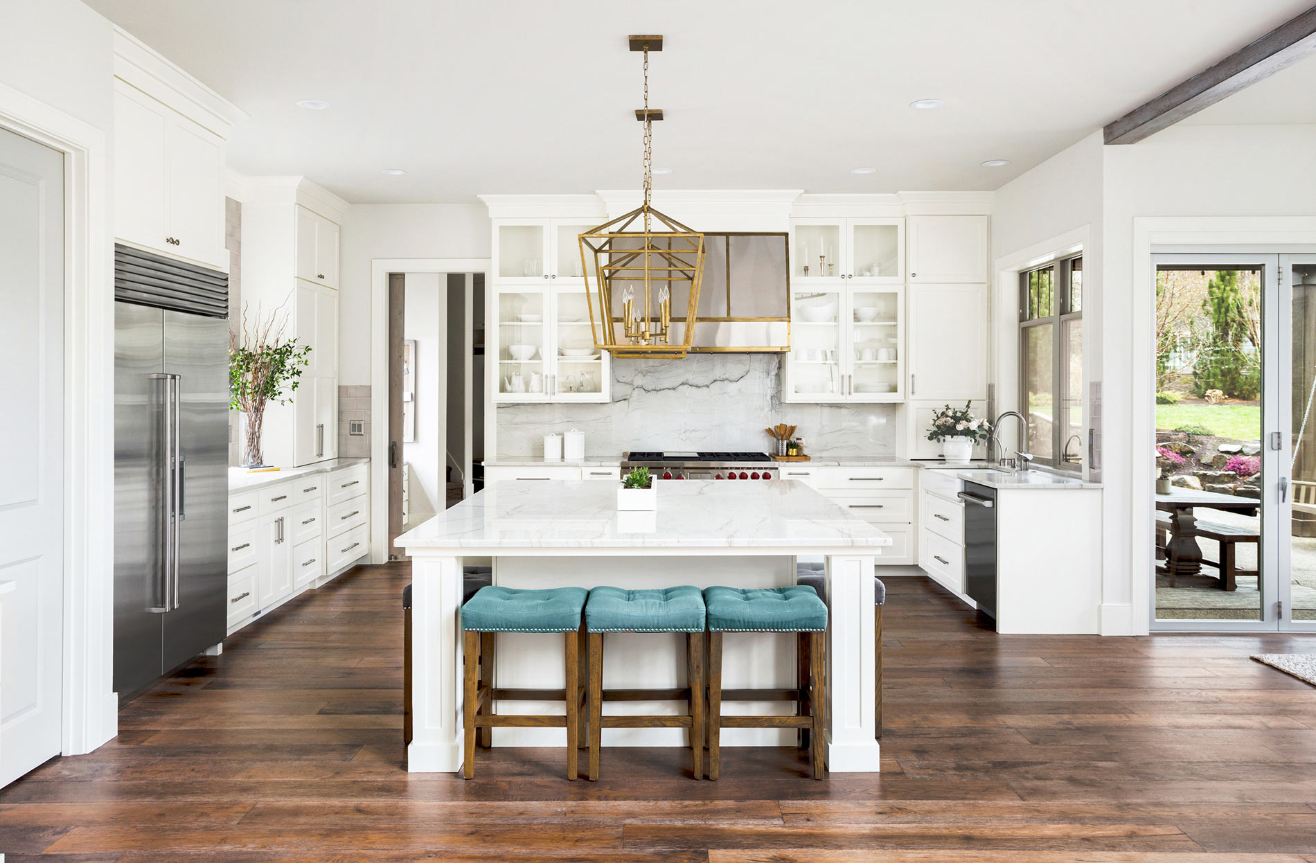 Bright white kitchen with marble island and teal counter stools