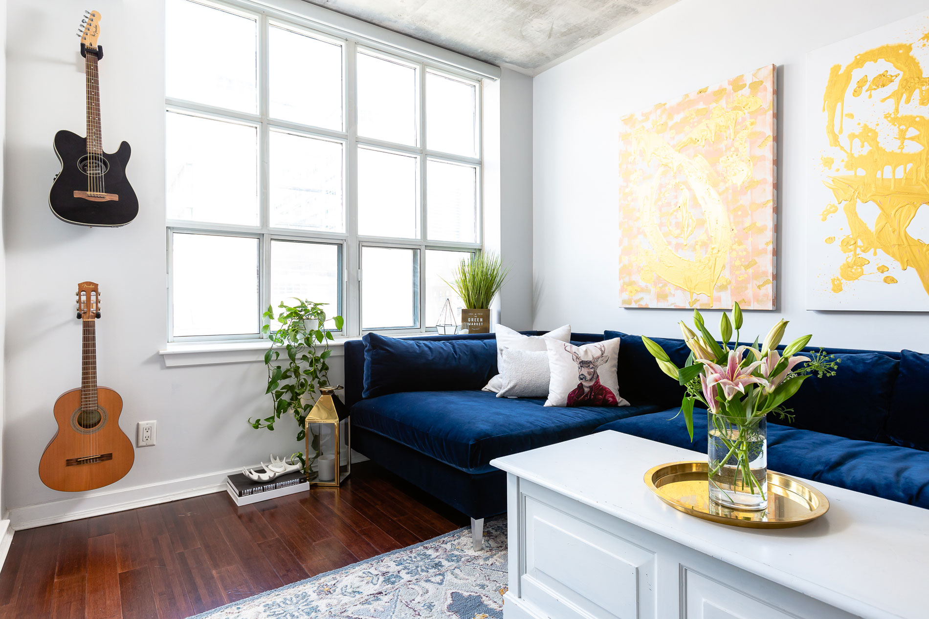 Urban loft living room with a navy velvet sofa and large windows
