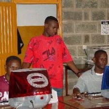 Drei Jugendliche mit Laptops im Schulungsraum