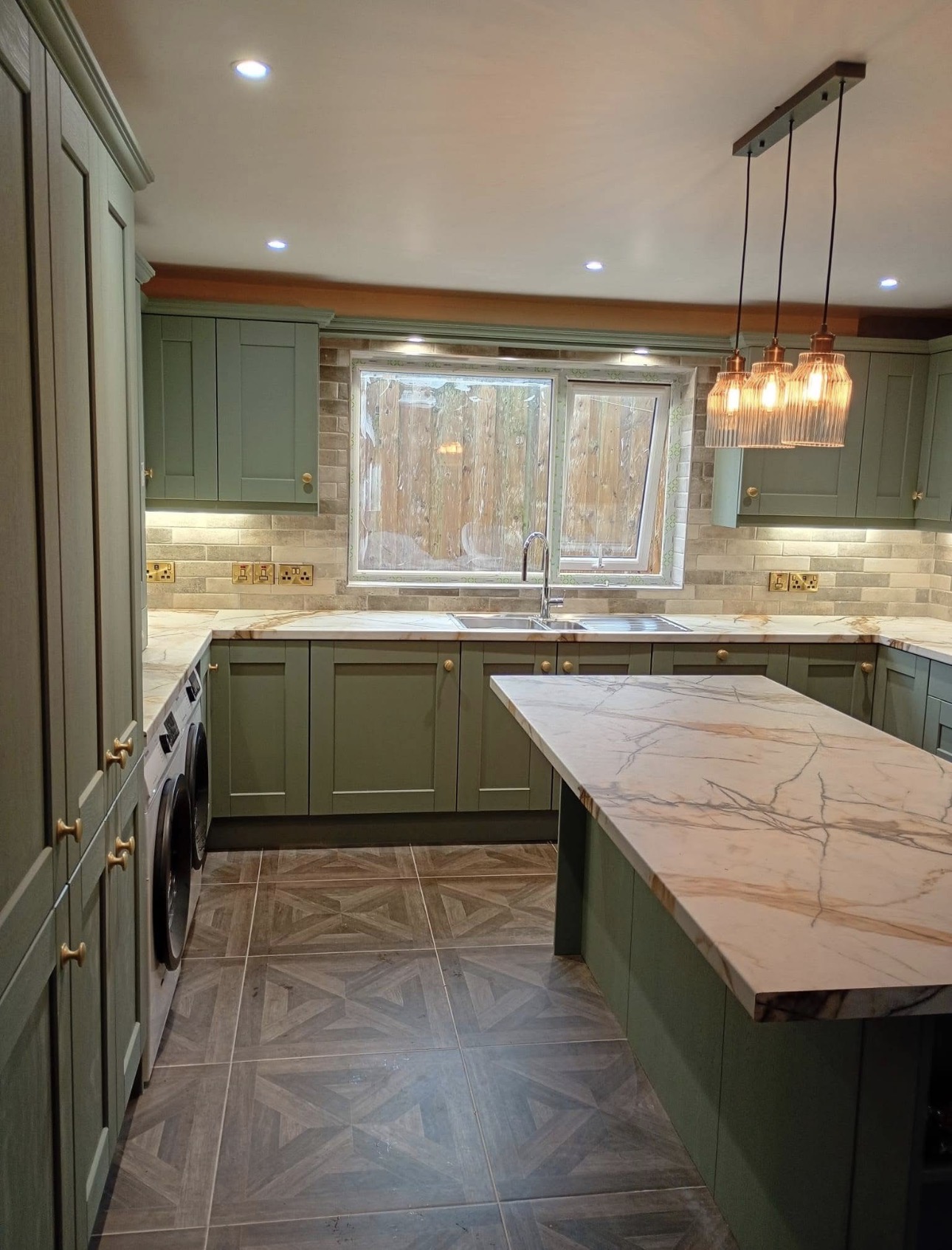 Handcrafted sage green shaker kitchen with marble worktops and brass hardware
