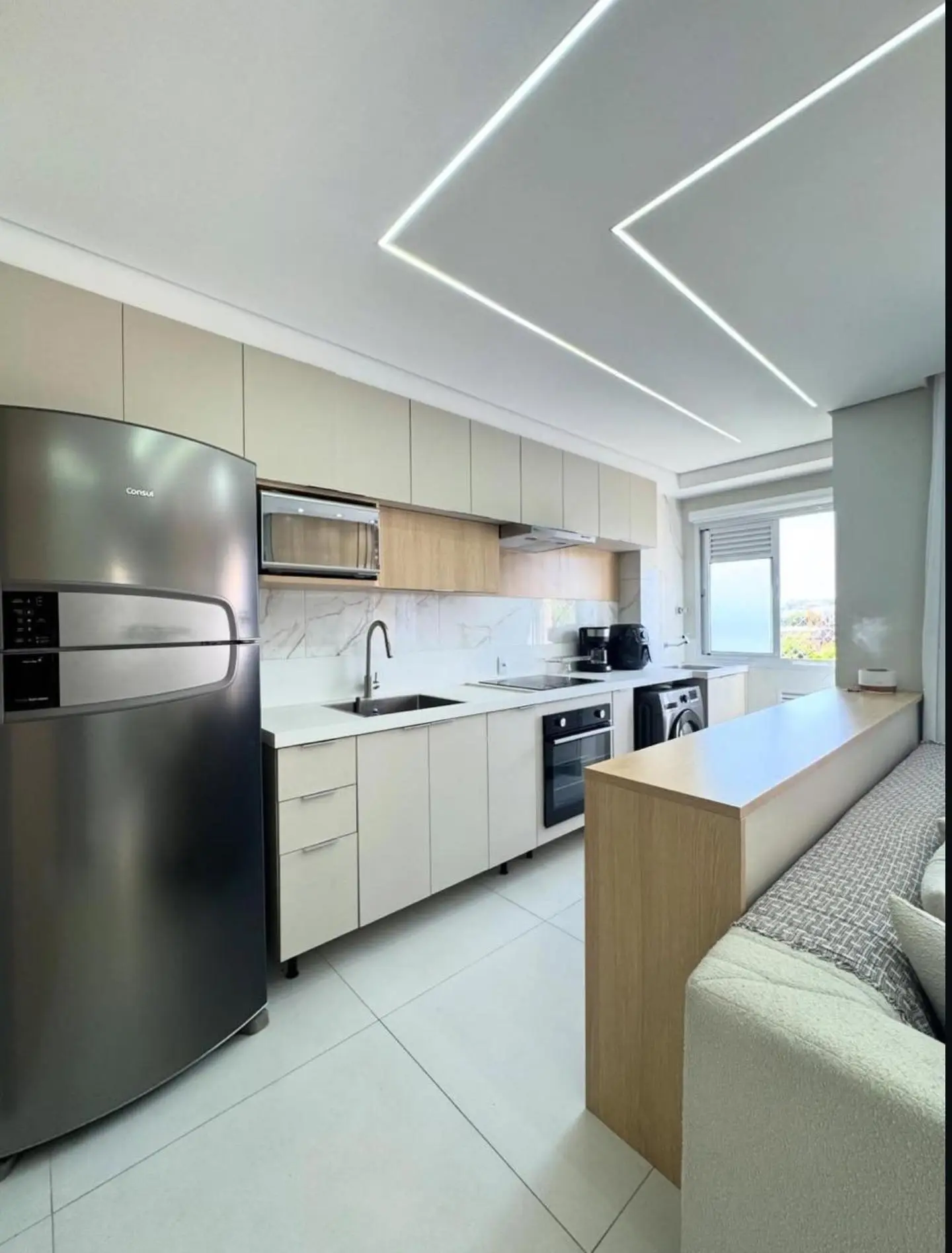 Cozinha integrada com armários bege e iluminação LED
