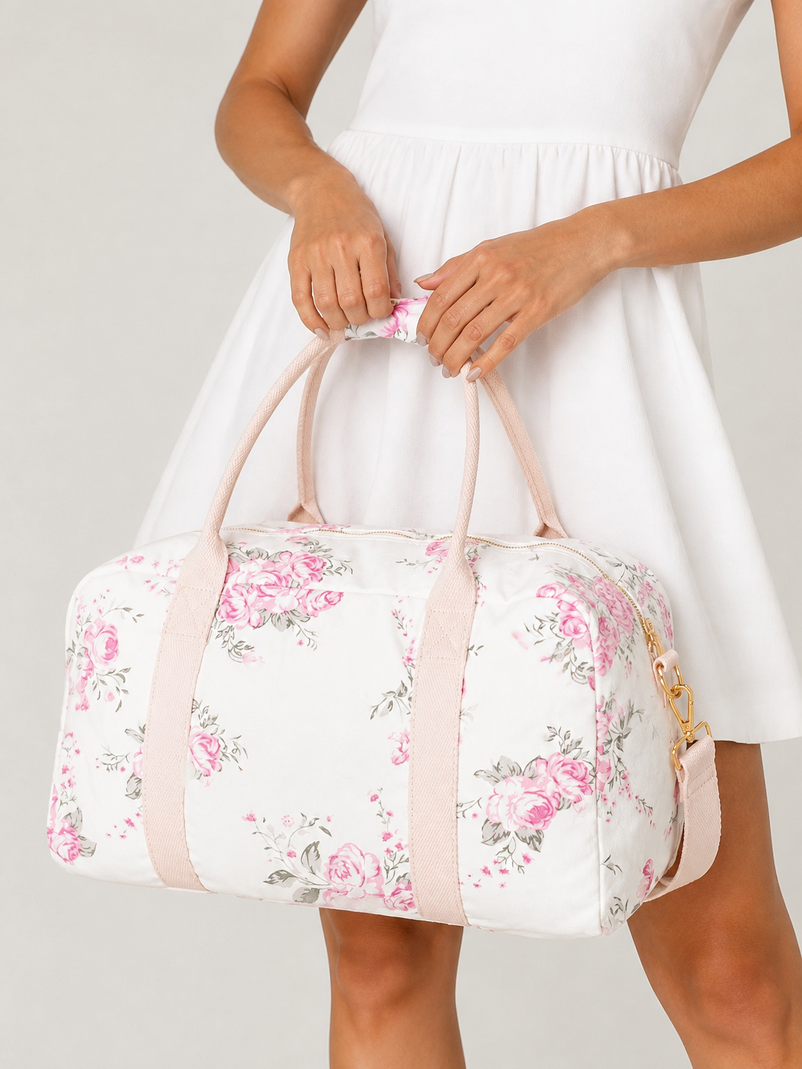 A roomy cotton floral-print weekender with blush carry handles, a detachable shoulder strap, and gold-tone hardware.
