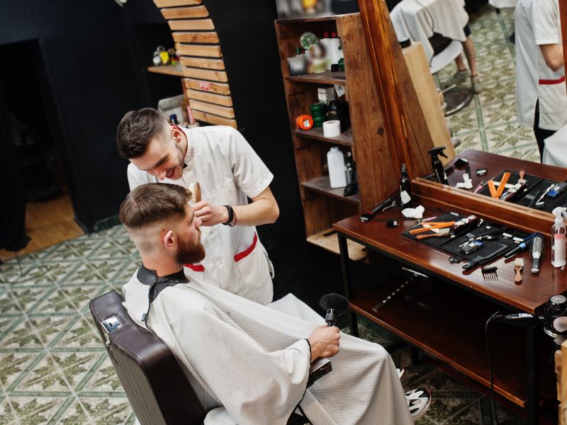 Barber giving a client a haircut in an equipped barbershop.