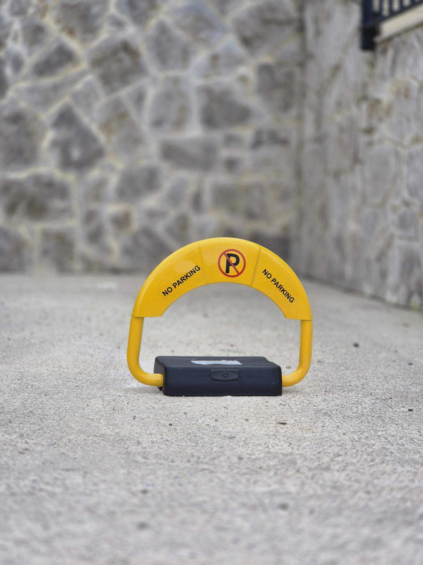 Žuta električna parking barijera sa oznakom NO PARKING postavljena na betonu