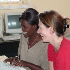 Trainerin und Teilnehmerin lachen gemeinsam am Computer