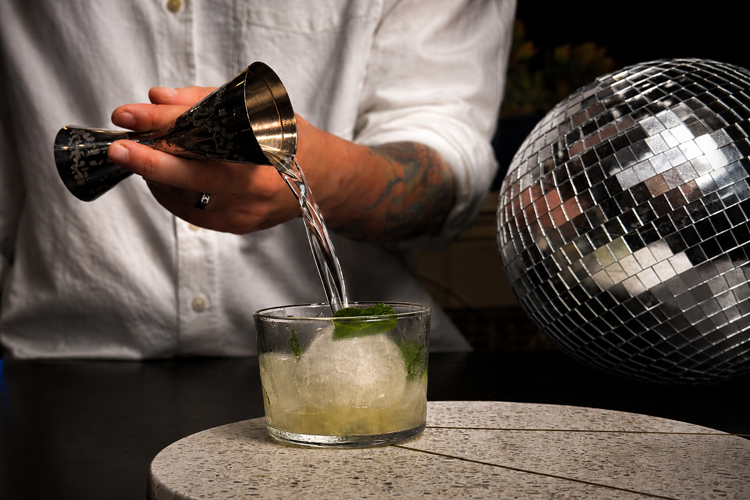 Professional bartender pouring a craft cocktail with precision