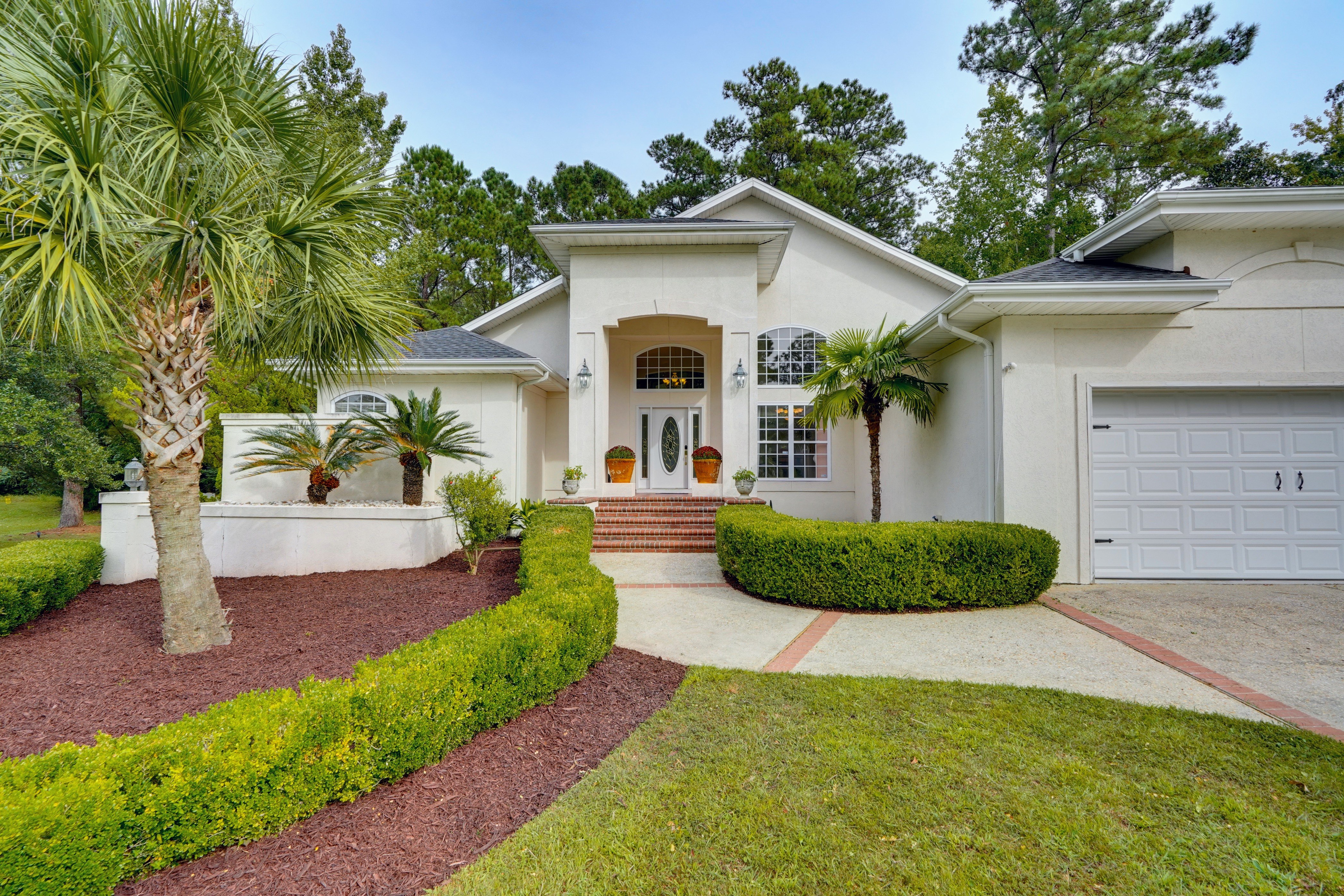 Elegant single-story home with palm trees and curved landscaping