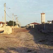 Staubige Dorfstraße im Abendlicht mit Kirchturm