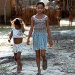 Zwei Mädchen in gemusterten Kleidern auf Sandweg