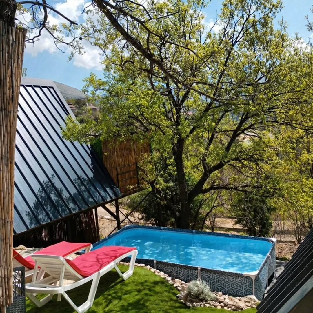Pool area with A-frame cabin and red loungers