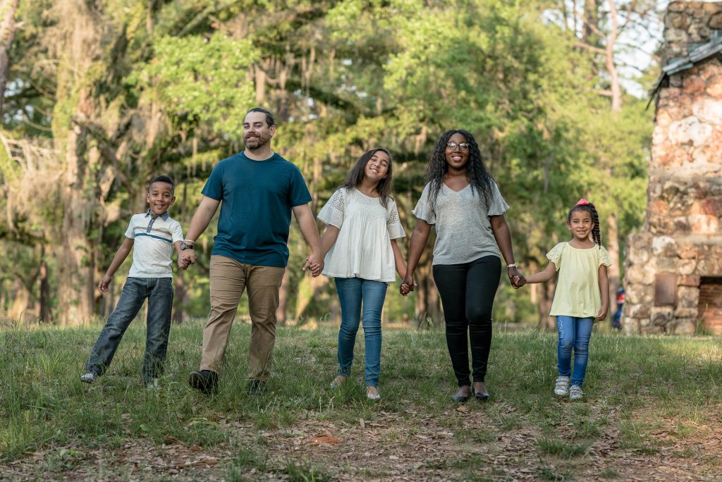 Family of five walking hand-in-hand through a park