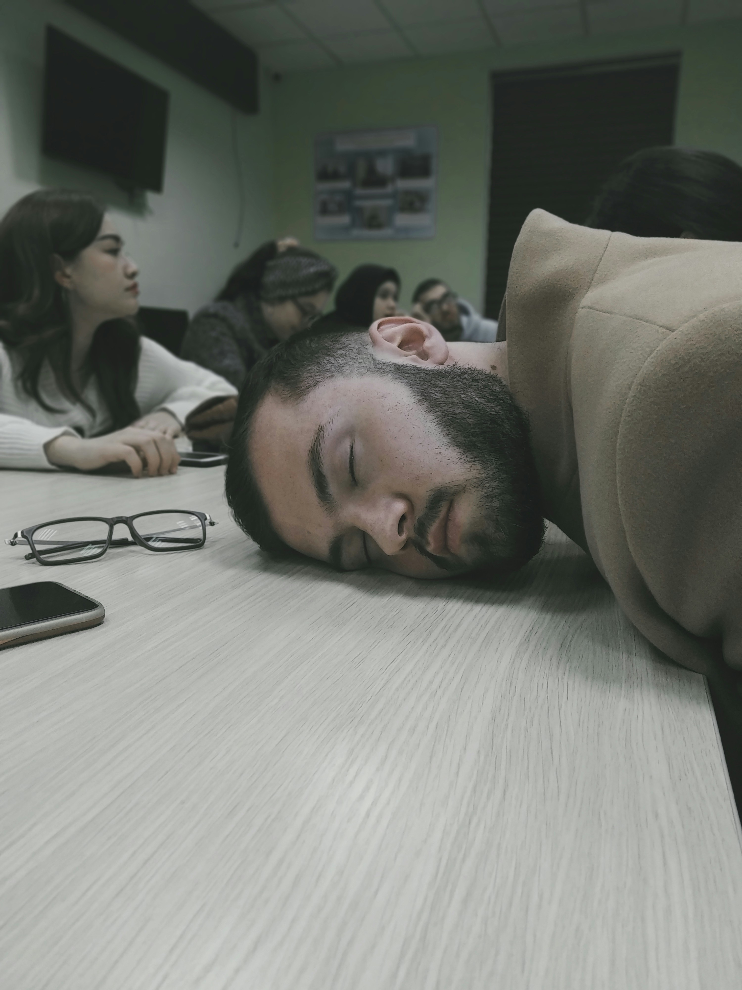 Person sleeping at desk with glasses nearby