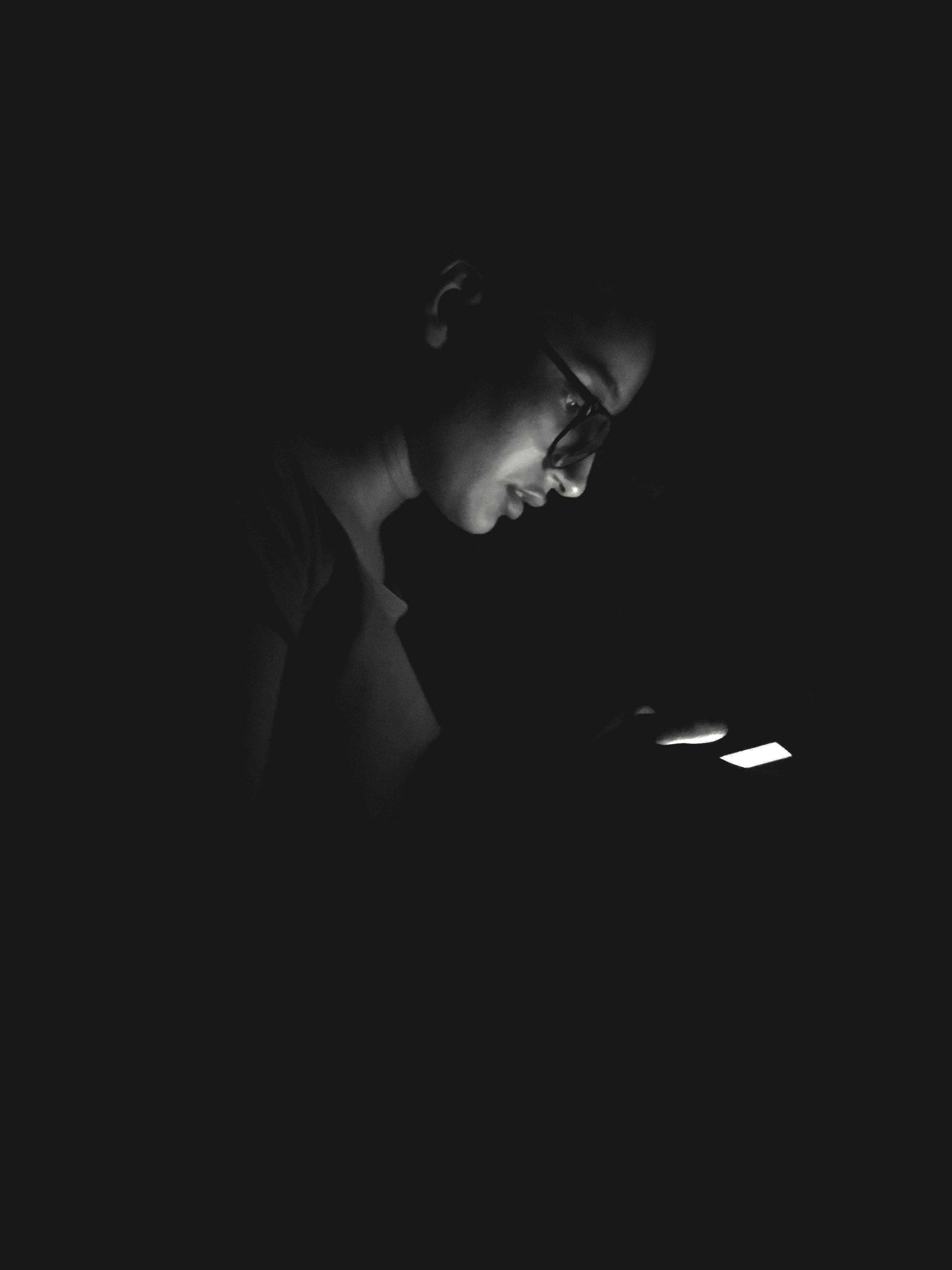 Person using a digital device in the dark, demonstrating the need for blue light protection