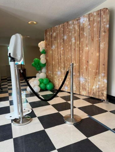 Photo booth setup with sparkly wood backdrop and green white balloon garland Nashville