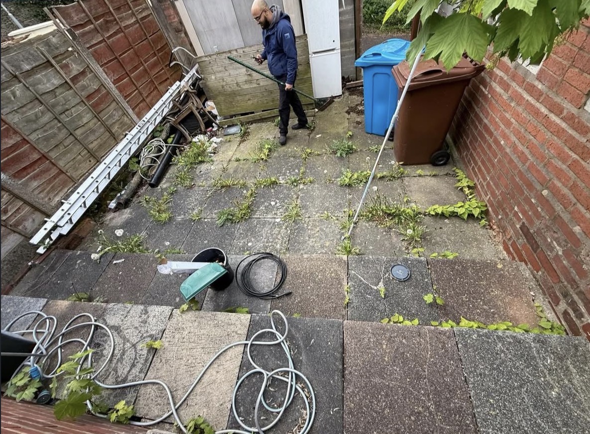 Garden before cleaning - weeds and debris on paving