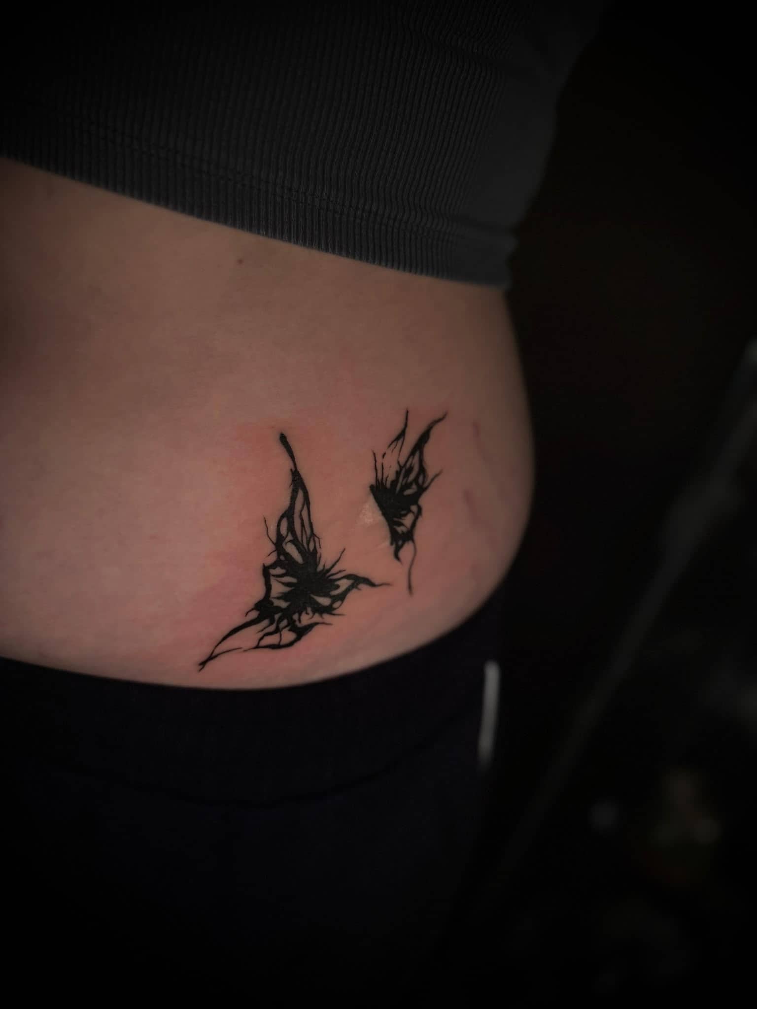 Blackwork zwei abstrakte Schmetterlings-Silhouetten am Bauch