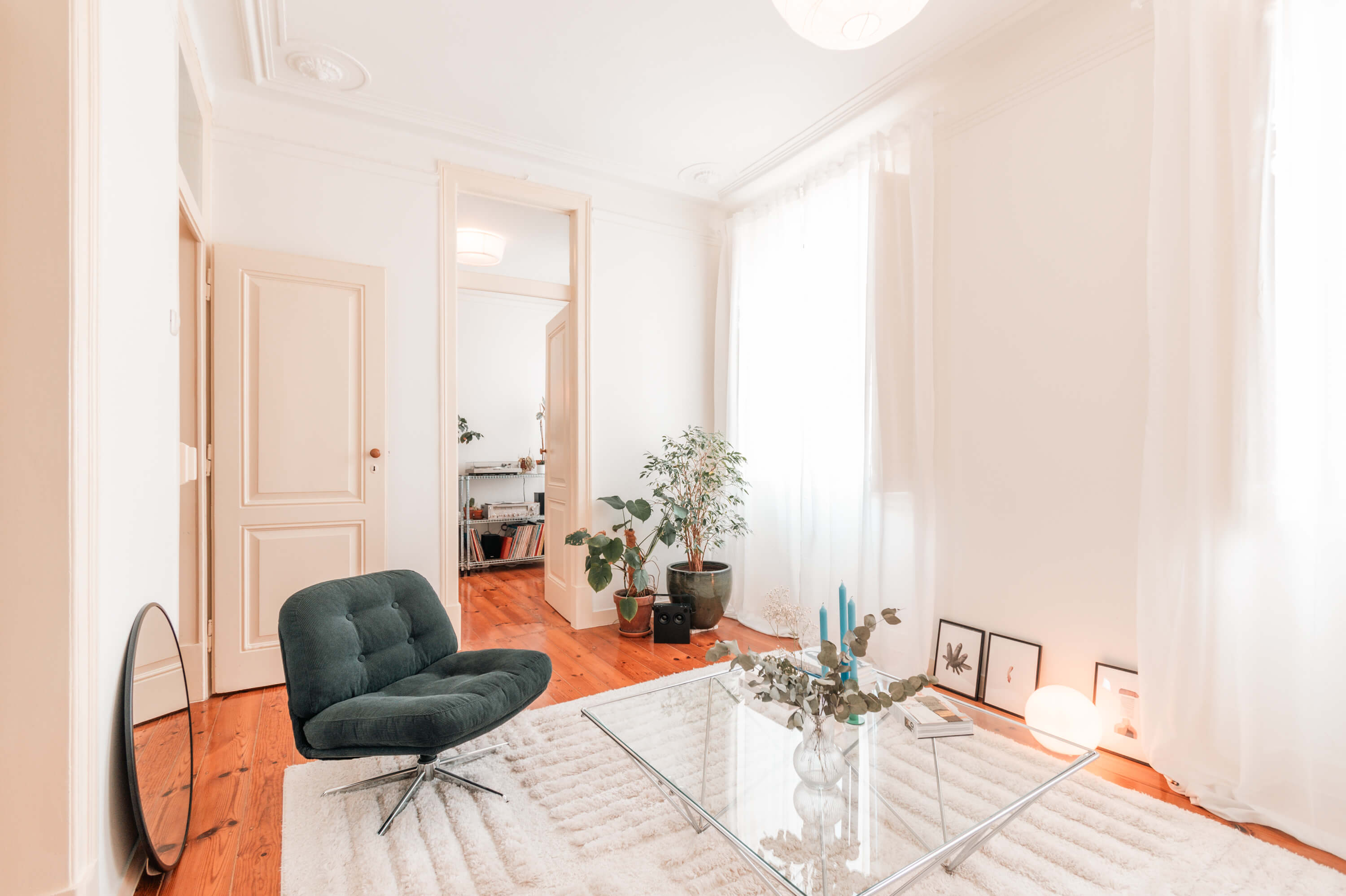 Living room with teal lounge chair, geometric glass coffee table, and indoor plants