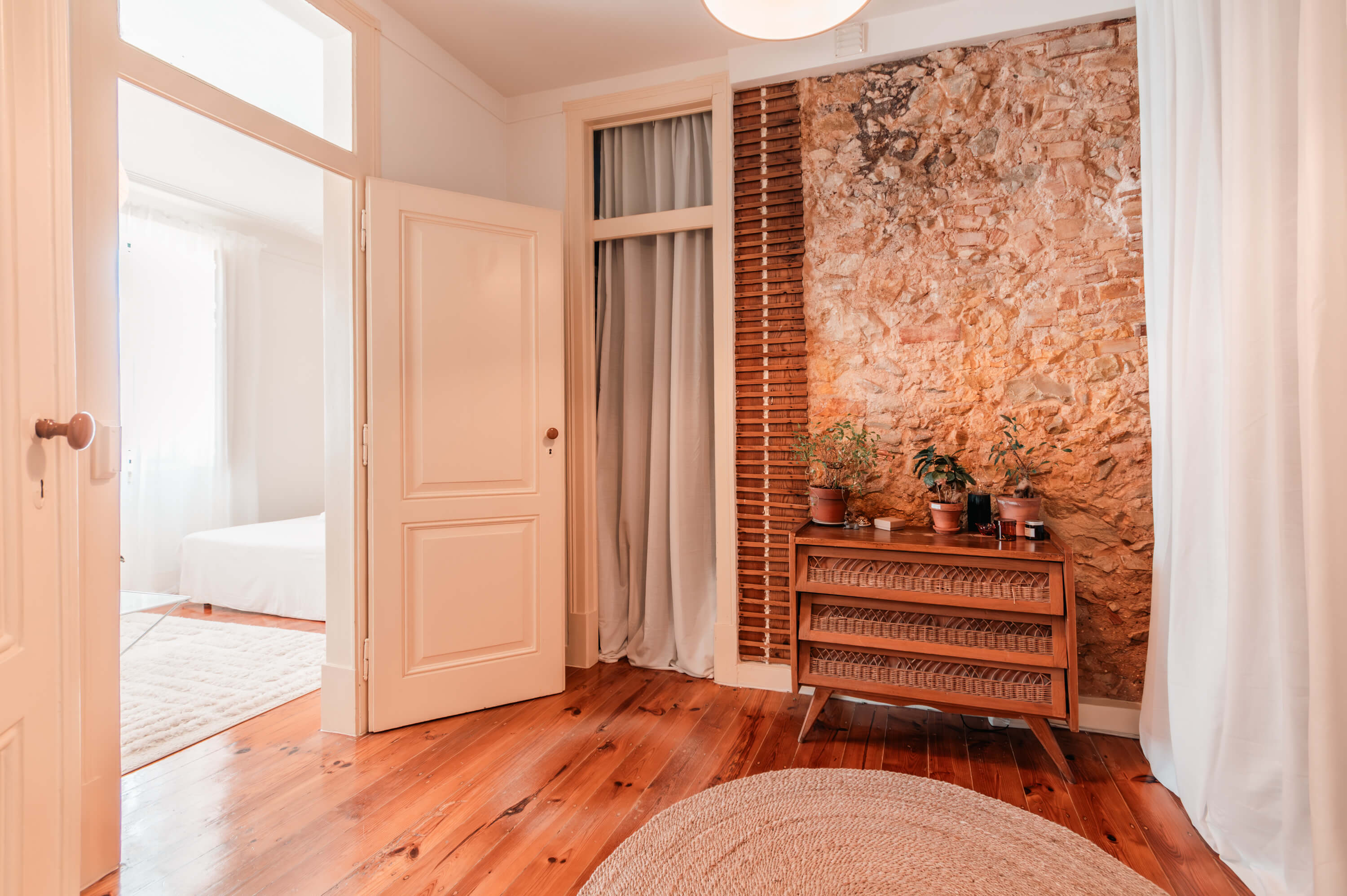 Hallway featuring exposed stone wall, vintage wooden cabinet, and traditional white paneled doors