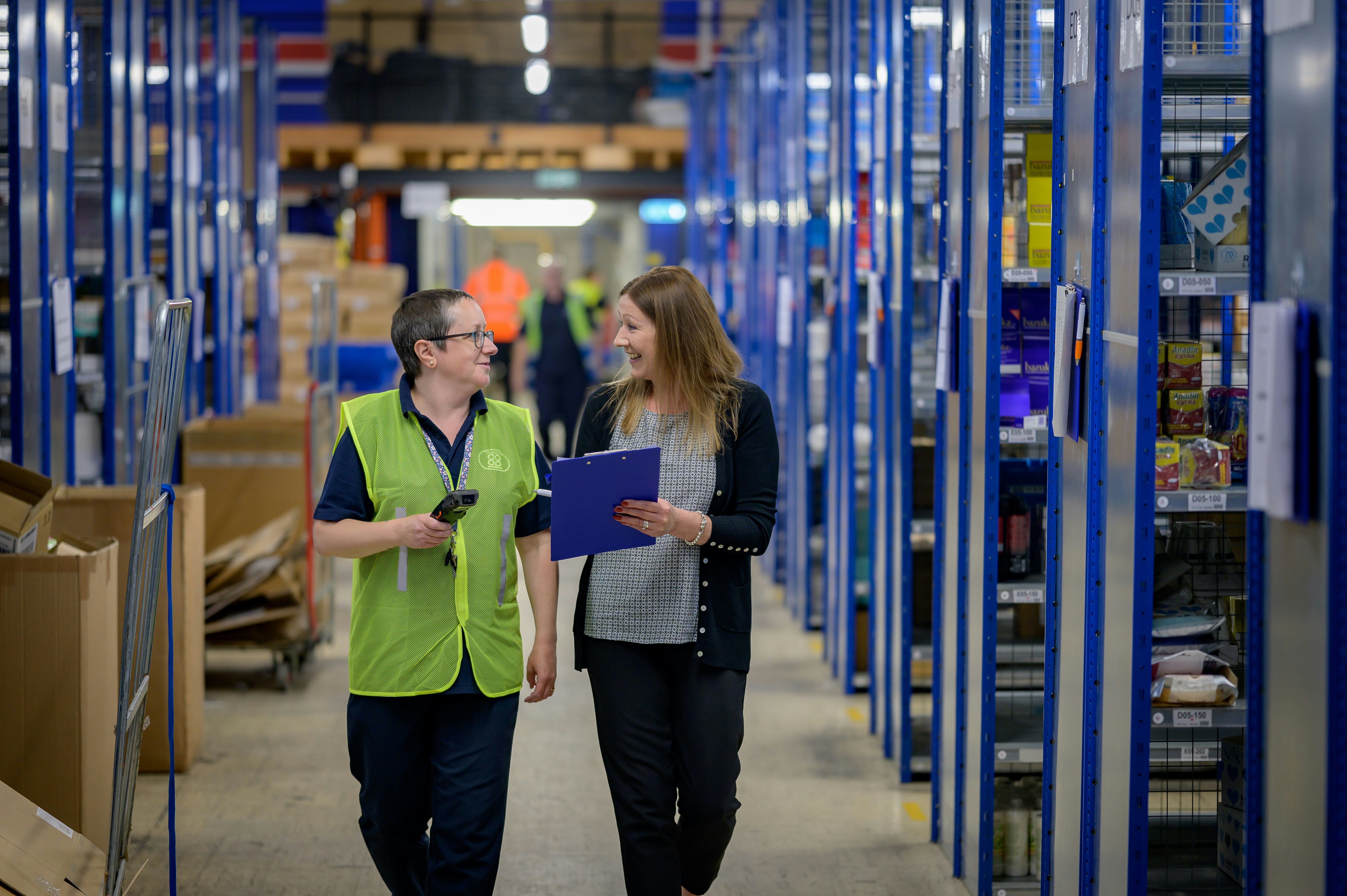 Warehouse workers walking through industrial shelving aisles