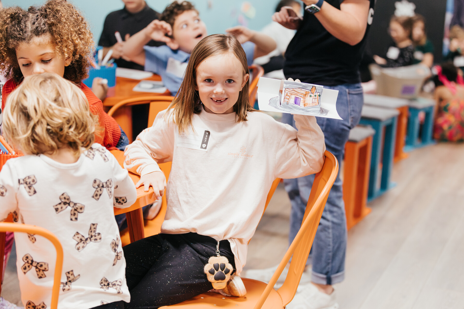 Smiling child holding up their craft in a CG Kids classroom