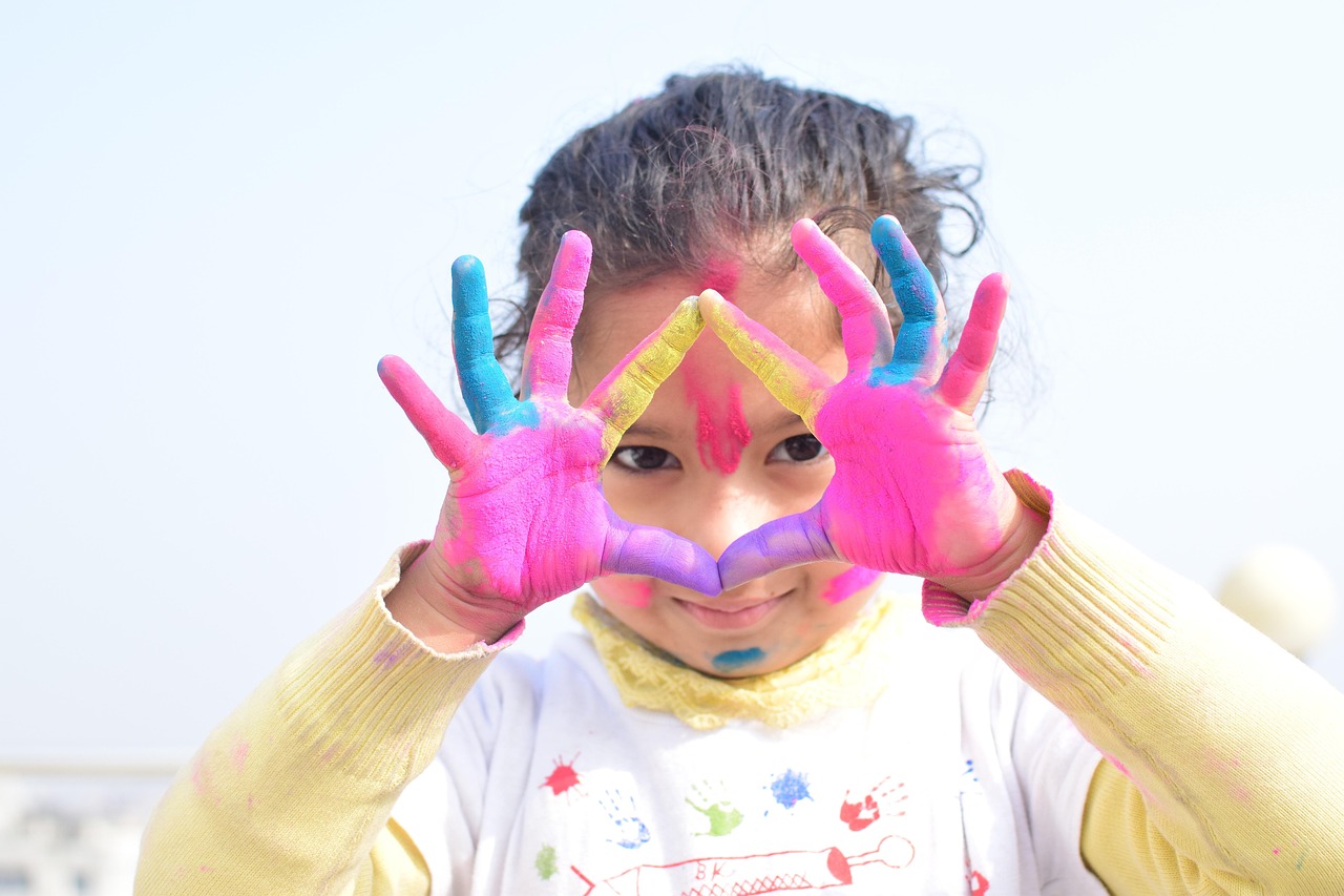 Creative child making heart shape with painted hands