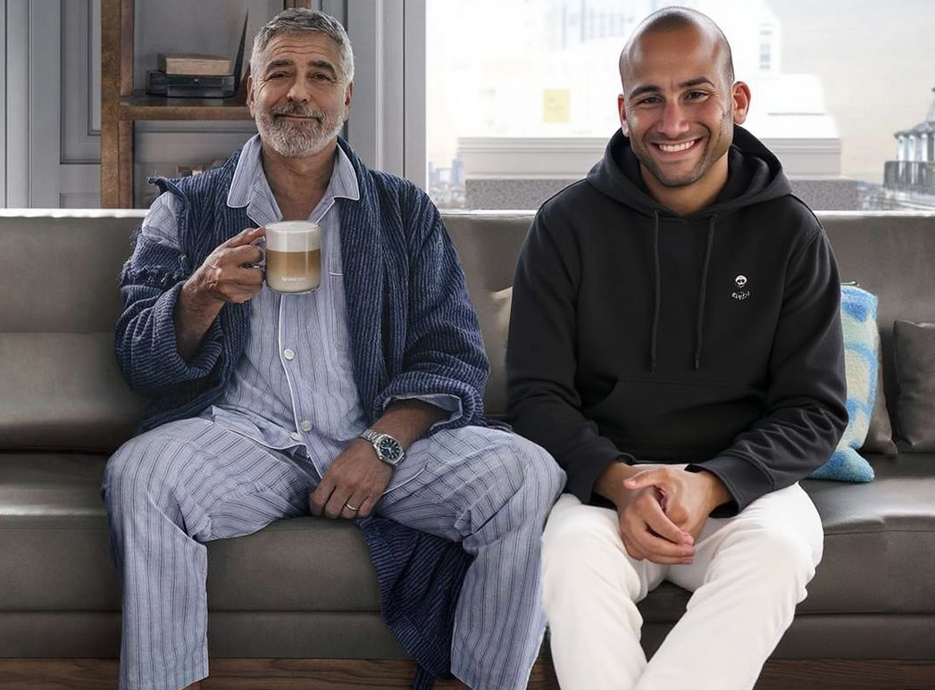 Man sitting with George Clooney in pajamas on a couch with coffee