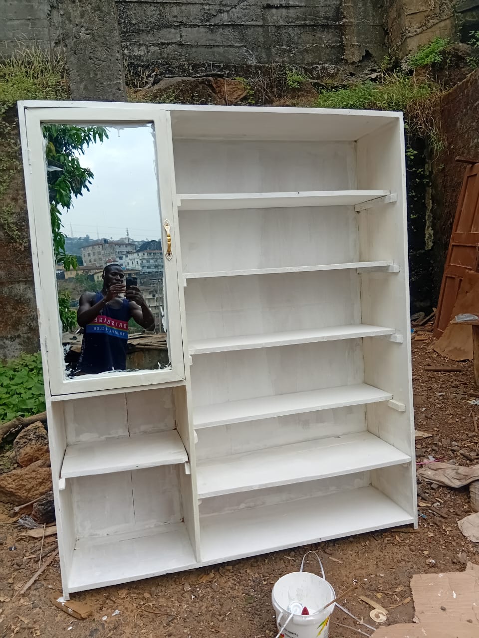 A white wardrobe with shelves and a mirror, built by Unisa Sesay as part of his carpentry work