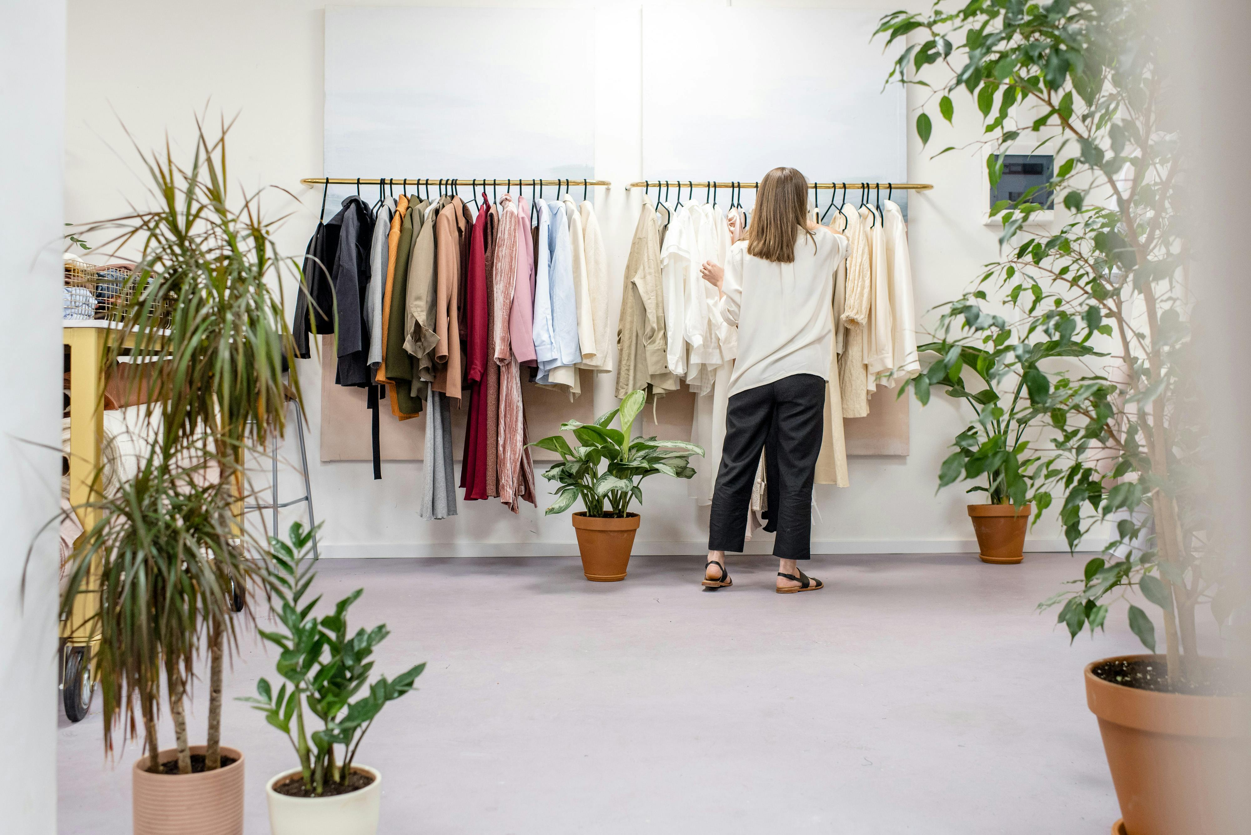 A minimalist clothing store interior with clothing rack and plants