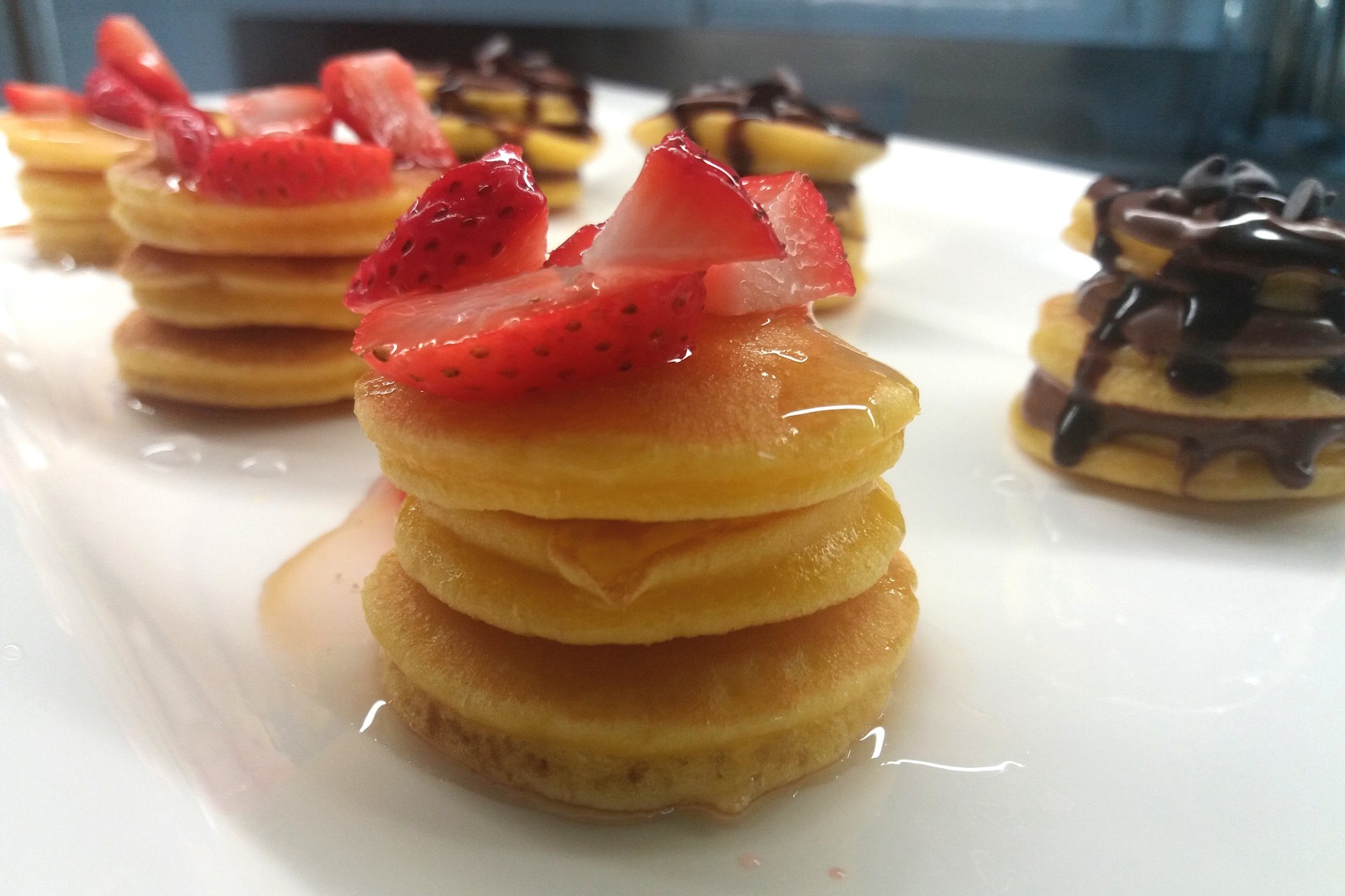 Mini pancakes with fresh strawberries and maple syrup