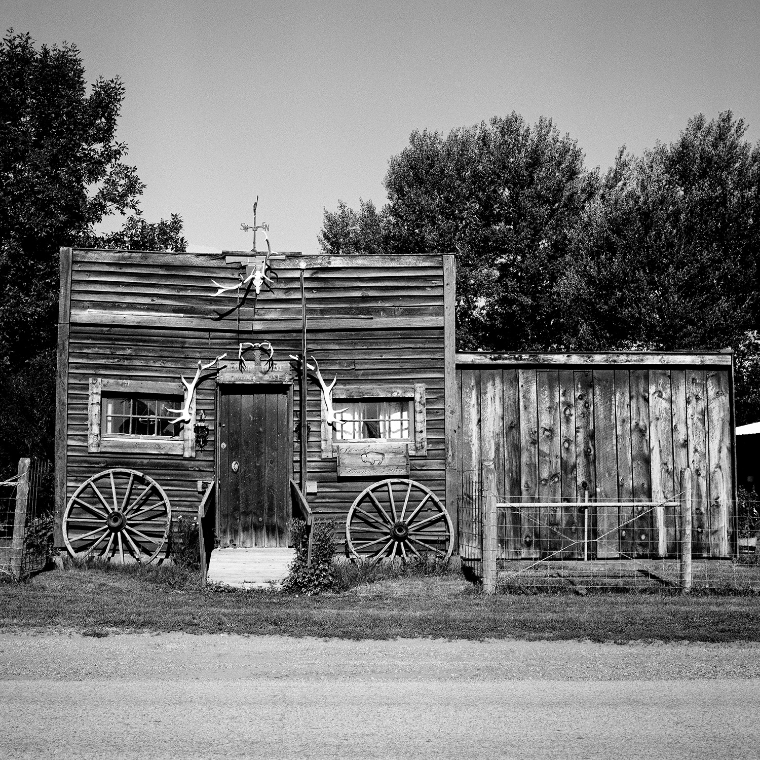 Rustic wooden frontier building with wagon wheels antler decorations and weather vane