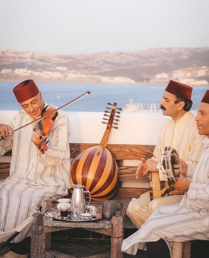 Traditional Moroccan musicians playing rebab and oud with coastal bay backdrop