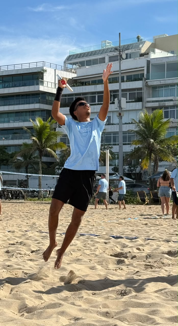 Jogador saltando para rebater a bola na praia