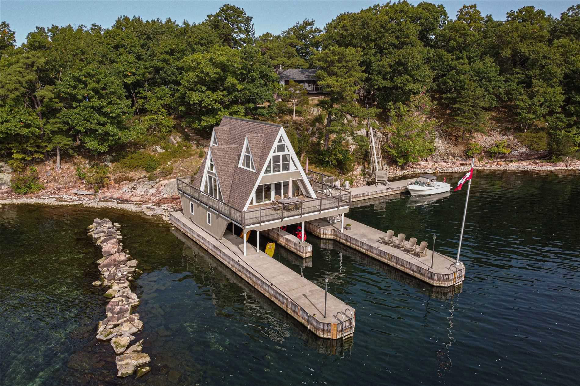 Waterfront A-frame cottage with docks and a boat on a forested shoreline