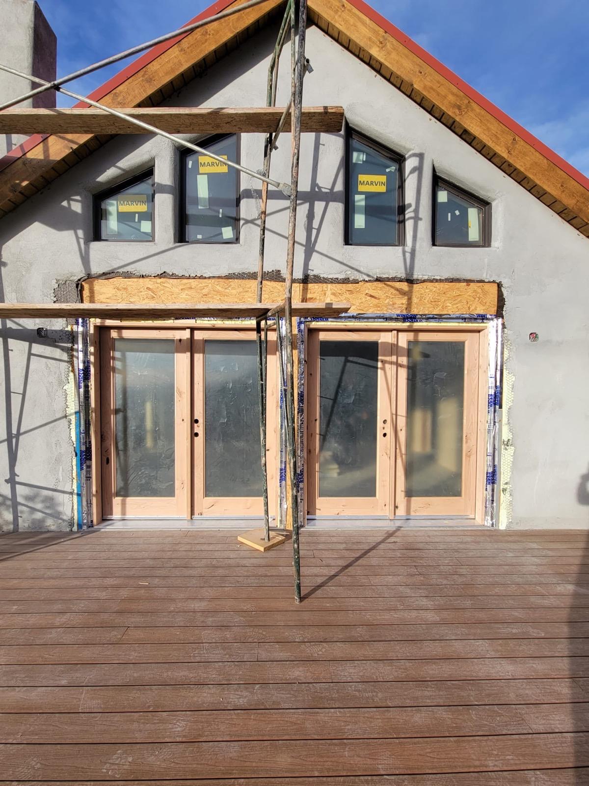 New construction exterior with gray stucco and scaffolding