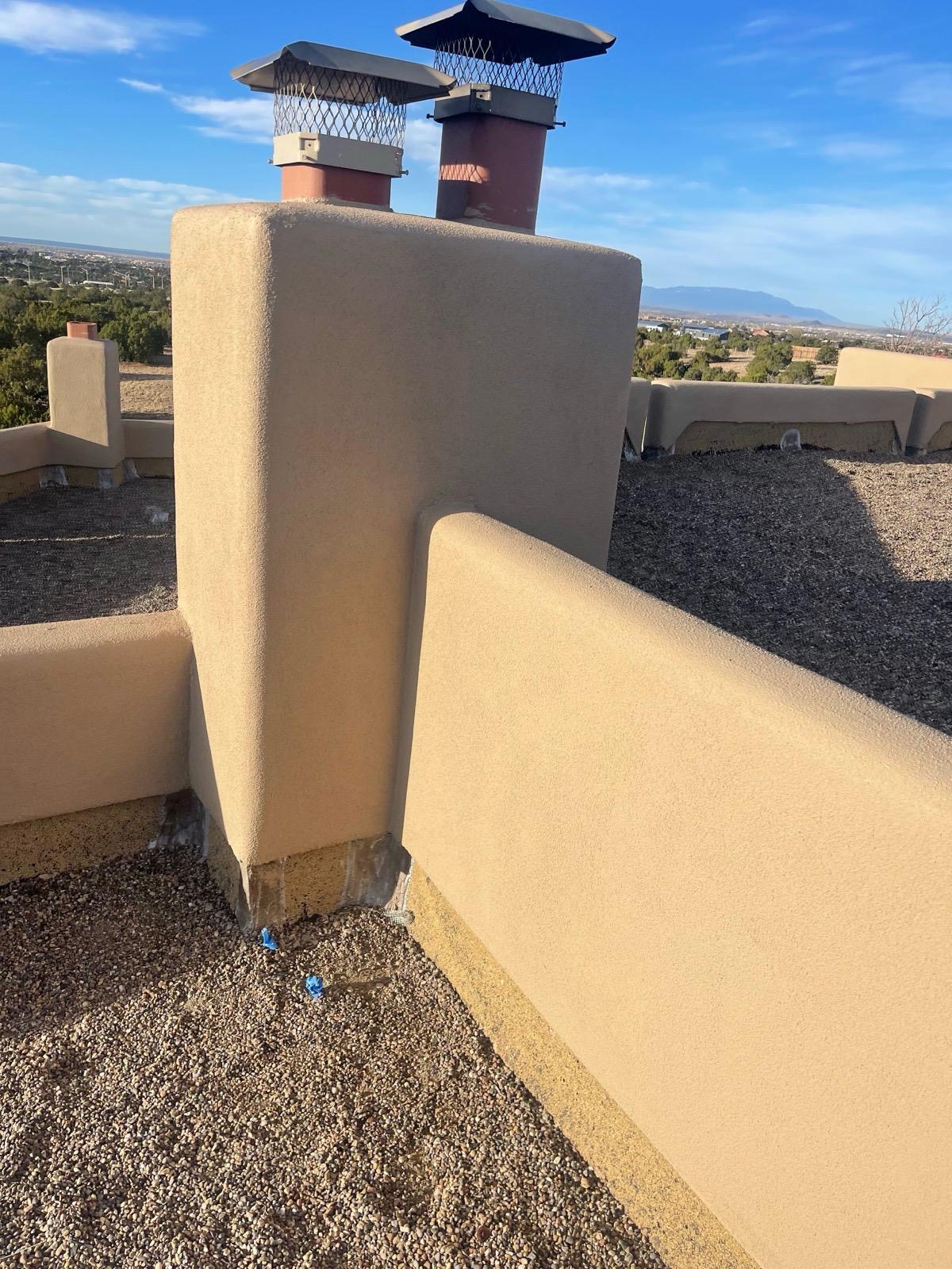 Chimney stucco work with dual flue caps and mountain view