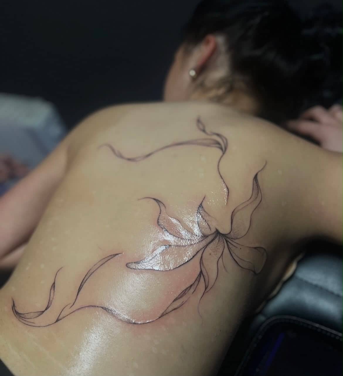 Fineline Blumen-Tattoo auf dem Rucken