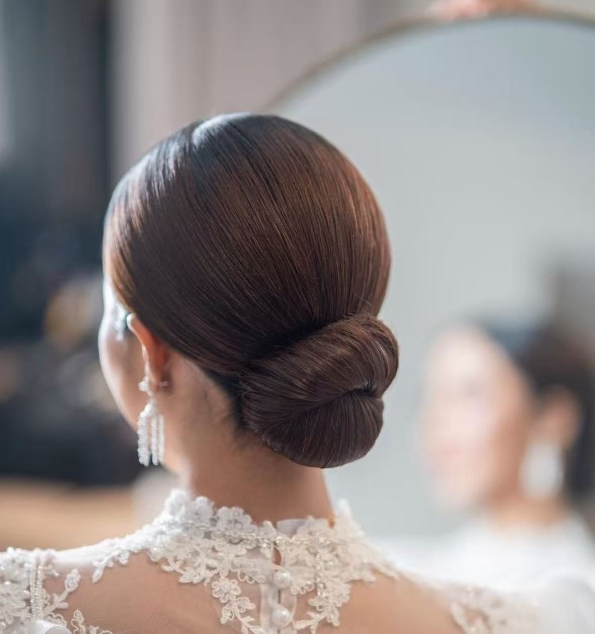 Sleek low bun hairstyle with pearl earrings