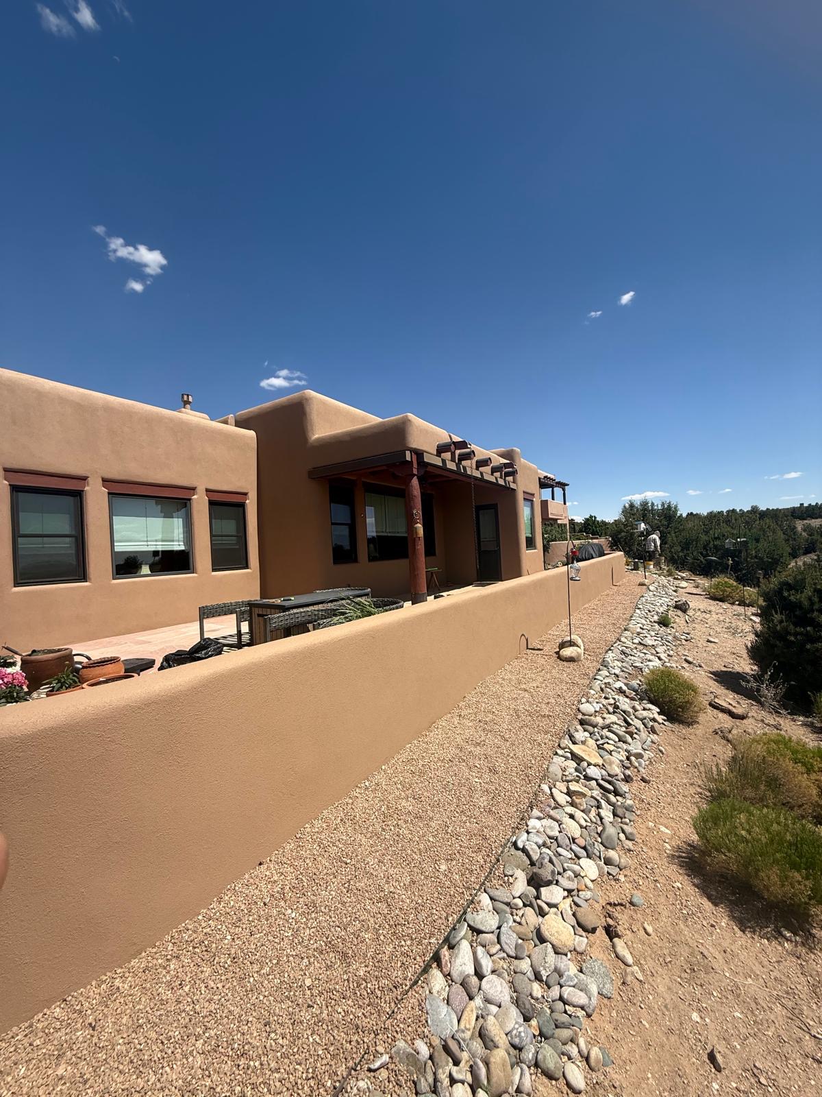 Adobe-style home exterior with smooth stucco walls and pergola